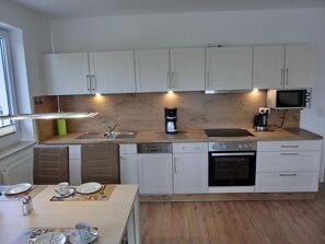 A modern kitchen with white cabinets, a wooden countertop, a built-in microwave, a coffee maker, and a dishwasher. - Apartment L37 - 2-room apartment for 4 pers. with 2 bicycles (Graal-Müritz)