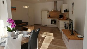 Une cuisine moderne avec des armoires blanches, un plan de travail en bois et un four encastré.
