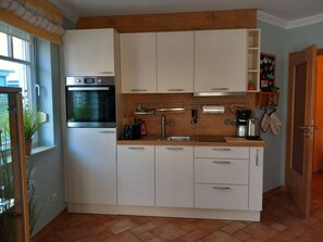 Eine moderne Küche mit weißen Schränken, einem eingebauten Backofen und einem Spülbecken.