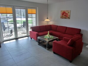 A living room with a red sectional sofa, a small coffee table, and a painting on the wall.