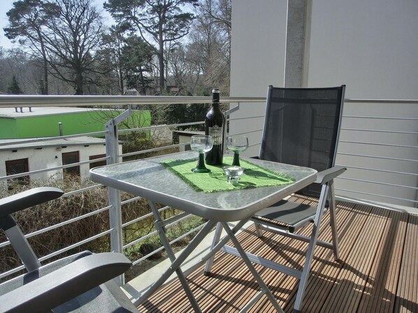 A balcony with a table, chairs, and a bottle of wine.