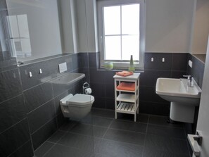 Een badkamer met toilet, wastafel en een plank met handdoeken.