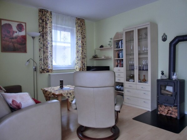 Un salon comprenant un canapé, un fauteuil, une table, un meuble et un poêle à bois.