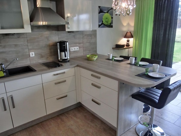 A modern kitchen with a built-in island, stainless steel appliances, and a dining area with a bar stool.