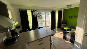 Eine moderne Küche mit Essbereich, einer Chandelier und Blick ins Freie.