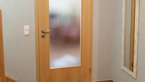 A room with a wooden door, a small window, and a tiled floor. - Apartment K21 "Storchennest" - 3-room apartment for 6 pers. on the 2nd floor with balcony (Graal-Müritz)