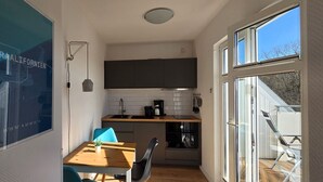 Una cucina compatta con un piano di lavoro in legno, un lavandino e un fornello. C'è una zona pranzo con tavolo e sedie.
