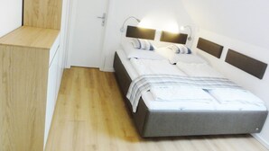 Un dormitorio con cama, mesitas de noche y una puerta.