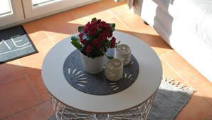 A round white table with a grey felt mat, a potted plant, and two candle holders on a tiled floor. - Vacation apartment K38 "Sonnenblume" - 3-room apartment with 2 floors for a maximum of 6 people. (Graal-Müritz)