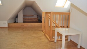 A small attic bedroom with a wooden bunk bed, a white table, and a wooden crib. - Vacation apartment K38 "Sonnenblume" - 3-room apartment with 2 floors for a maximum of 6 people. (Graal-Müritz)