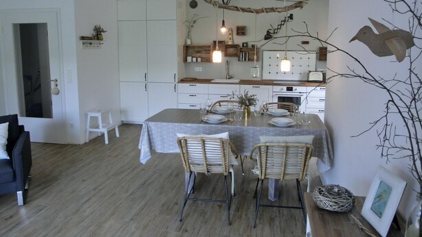 A modern kitchen with white cabinets, a dining table set for four, and a rustic decor theme.