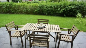 A wooden outdoor table and four matching chairs on a tiled patio.