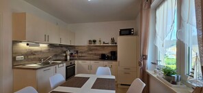 Eine kompakte Küche mit Essbereich, einer Mikrowelle und einem Fenster mit Vorhängen.