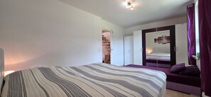Ein Schlafzimmer mit Bett, Sofa, Kleiderschrank und Spiegel.