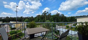 Ein Balkon mit Tisch und Stühlen, mit Blick auf ein Wohngebiet mit Häusern und einer Straße.