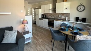 Un salon moderne avec un canapé et un coin repas comprenant une table mise pour deux personnes.