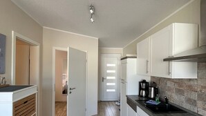 Une cuisine moderne avec des armoires blanches, un comptoir noir et un plancher en bois.