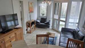 Un salon moderne avec un téléviseur, des meubles en bois, un canapé et une table à manger.