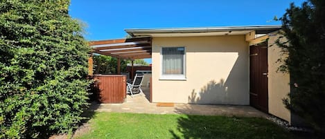 A single-story house with a covered patio, a fenced yard, and a small garden area.