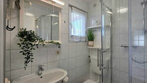 Ein Badezimmer mit Duschkabine aus Glas, Waschbecken und Spiegel.
