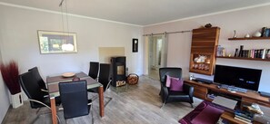 A modern living room with a dining area, a fireplace, a TV, and a bookshelf.