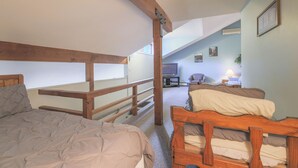 Un dormitorio con dos camas, cabeceros de madera, un televisor y una mesita de noche con una lámpara.