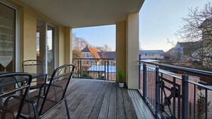 A wooden deck with metal chairs and a railing, overlooking a residential area with houses and trees. - Vacation apartment L41 "Morgensonne" - 3-room apartment (approx. 54 m²) for 4 people with balcony (Graal-Müritz)