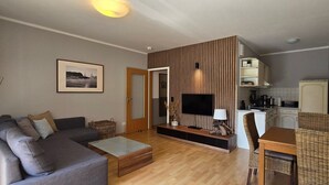 Una sala moderna con sofá, mesa de centro, televisor y comedor.