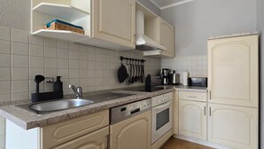 Una cocina con armarios blancos, encimera de granito, un fregadero, estufa y microondas.