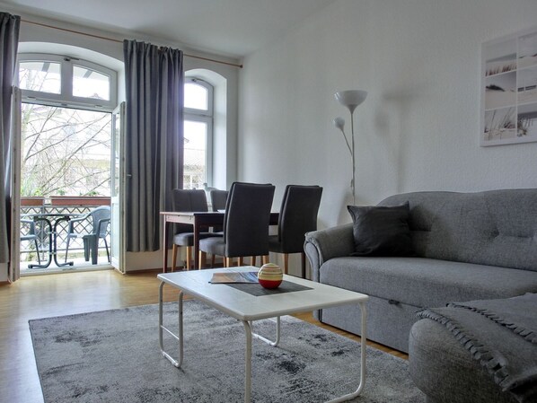 Un salon moderne avec un canapé gris, une table basse blanche et un coin repas comprenant une table et des chaises.