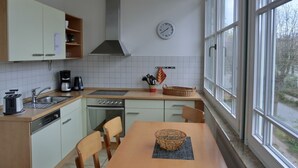 A compact kitchen with a stove, sink, and a dining area with a table and chairs.