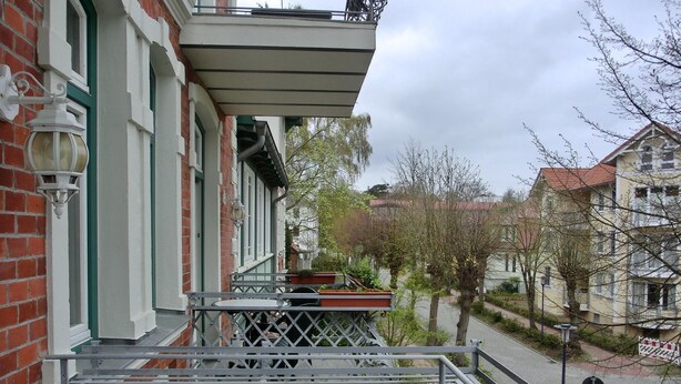A residential building with a balcony, a brick facade, and a street view.