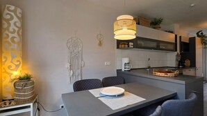 Eine moderne Küche mit Essbereich, inklusive einer großen Kochinsel, Pendelleuchten und dekorativen Wandbildern.