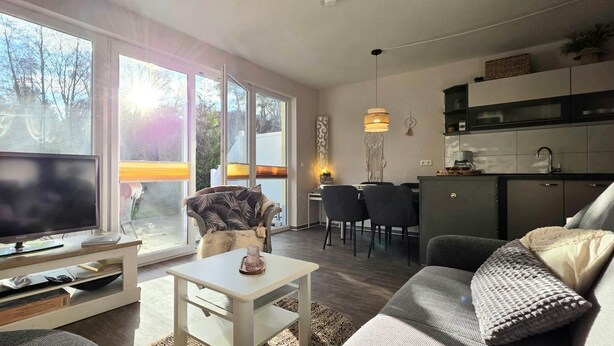 Ein modernes Wohnzimmer mit Fernseher, Sitzgelegenheiten und einem Essbereich mit Stühlen und einem Tisch.
