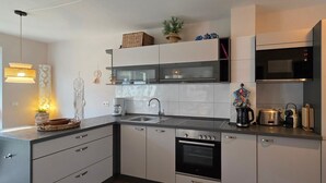 Eine moderne Küche mit weißen Schränken, einer Edelstahl-Spüle und einem eingebauten Backofen.