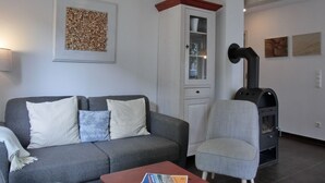 Una sala de estar con un sofá gris, una mesita, un armario y una chimenea.