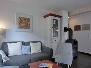 A living room with a grey sofa, a small table, a cabinet, and a fireplace.