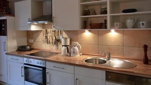 A modern kitchen with white cabinetry, a stainless steel sink, and a built-in oven. - Apartment T14 - "Blinkfüer" - 2-room apartment on the ground floor for 2 pers. (Graal-Müritz)