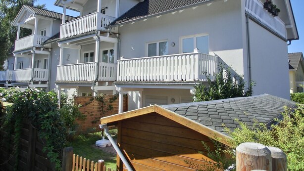 A multi-story residential building with balconies, a wooden deck, and a brick wall. - Apartment T14 - "Blinkfüer" - 2-room apartment on the ground floor for 2 pers. (Graal-Müritz)