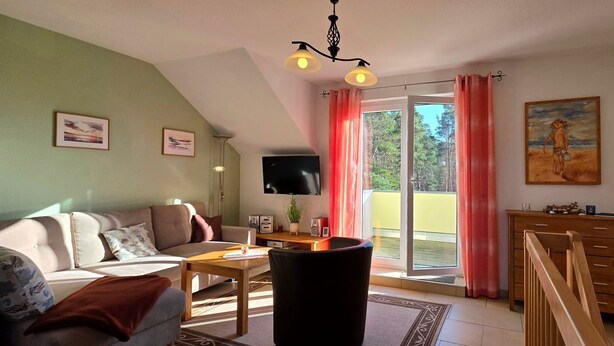 A living room with a sofa, a coffee table, a TV, a wooden cabinet, and a sliding glass door leading to a balcony.