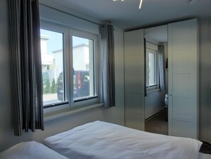 Et hotelværelse med seng, garderobeskab og et vindue med gardiner.