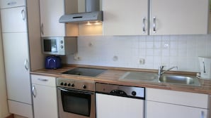 A compact kitchen with a microwave, oven, dishwasher, and a sink.
