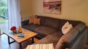 A living room with a brown sofa, a wooden coffee table, and a painting of a sunset over the ocean.