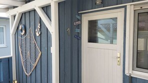 A wooden building with a white door, a window with a view, and decorative items like a net and life rings on the wall.