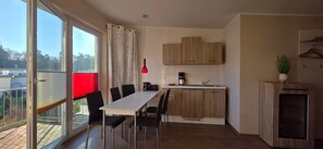 Une cuisine moderne avec des meubles en bois, une table à manger avec des chaises, une machine à café et une plante en pot.
