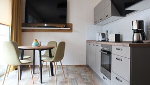 Eine moderne Küche mit Flachbildfernseher, Edelstahlgeräten und einem Essbereich mit Tisch und Stühlen.
