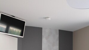 A modern room with a white wardrobe, a wooden cabinet, and a flat-screen TV mounted on the wall.