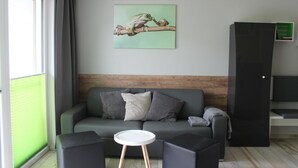 A modern living room with a grey sofa, a small white table, and a black cabinet.