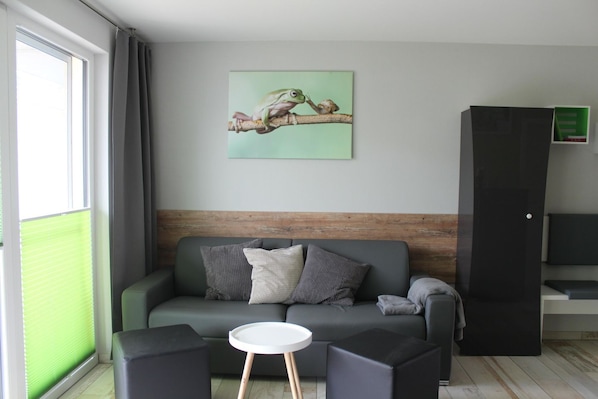 A modern living room with a grey sofa, a small white table, and a black cabinet.