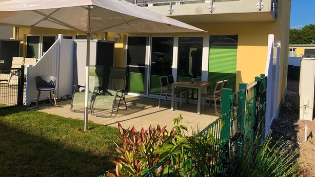 A two-story building with a balcony, outdoor seating area, and a covered patio.